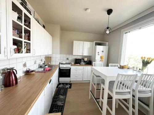 a kitchen with white cabinets and a white table and chairs at Relax Convenient Transit Stays -shared apartment in Vantaa