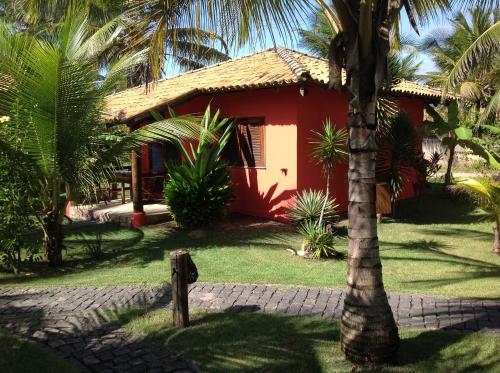 a red house with a palm tree in front of it at Bahiadomizil in Canavieiras