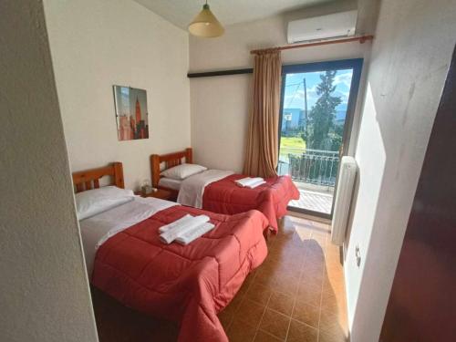 um quarto de hotel com duas camas e uma grande janela em Nafplion Seaside em Néa Kíos