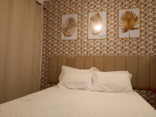 1 dormitorio con 1 cama con 4 cuadros en la pared en Suíte Studio 3 Enseada Tortuga Mobiliada en Guarujá