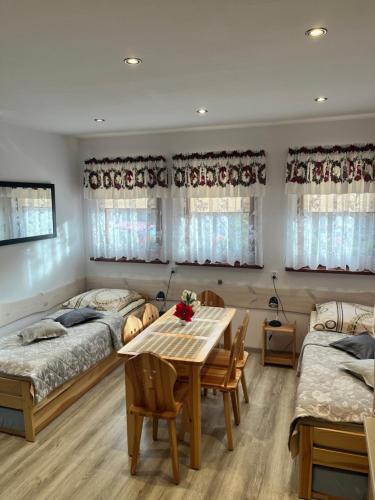 a bedroom with two beds and a table and chairs at Apartamenty u Grażyny in Kluszkowce