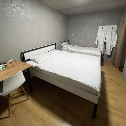 a bedroom with a bed with white sheets and a desk at ИксаОтель in Shymkent