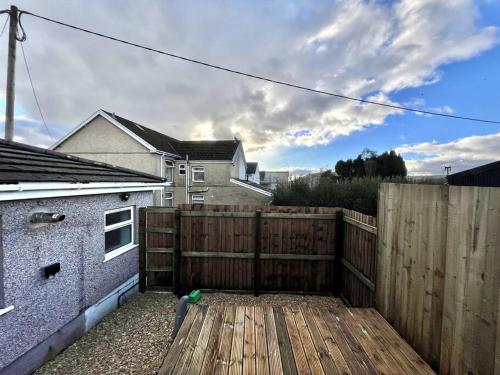 a backyard with a wooden fence and a wooden deck at Modern Mountain Retreat in the Brecon Beacons in Ystradgynlais