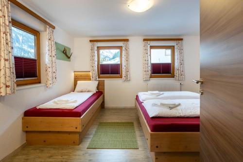 2 Betten in einem Zimmer mit 2 Fenstern in der Unterkunft Ferienwohnung Brandegg in Tux