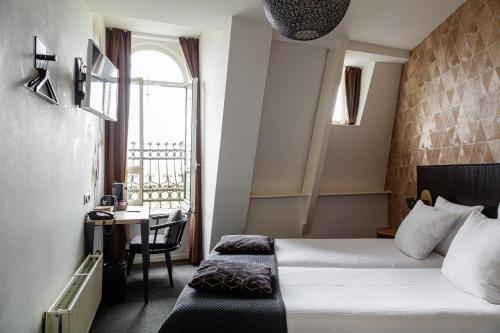 a hotel room with a bed and a desk and a window at Boutique Hotel View in Amsterdam