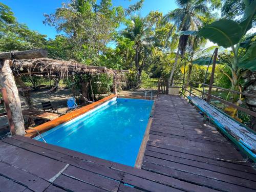 a pool with a wooden walkway next to a house at Casa Tili TicoExperience on IslaDamas in Quepos