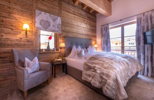 a bedroom with a bed and a chair and a television at Circle Chalets Arlberg in Zug