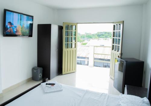 ein Schlafzimmer mit einem Bett und einem TV an der Wand in der Unterkunft Luz de Luna Hostal in Tesalia
