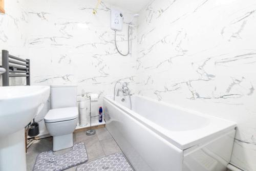 a white bathroom with a tub and a toilet and a sink at Holiday Lodge, close to Nottingham City Centre in Nottingham