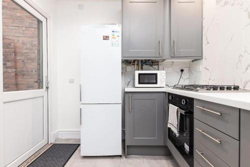 a white kitchen with a refrigerator and a microwave at Holiday Lodge, close to Nottingham City Centre in Nottingham