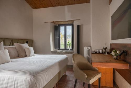 a bedroom with a bed and a chair and a window at Monastero Sant'Alberico Relais in Balze