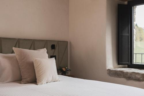 a bedroom with a bed with white pillows and a window at Monastero Sant'Alberico Relais in Balze