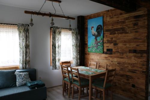 a dining room with a table and chairs and a couch at Domki Bukowy Las in Rewa