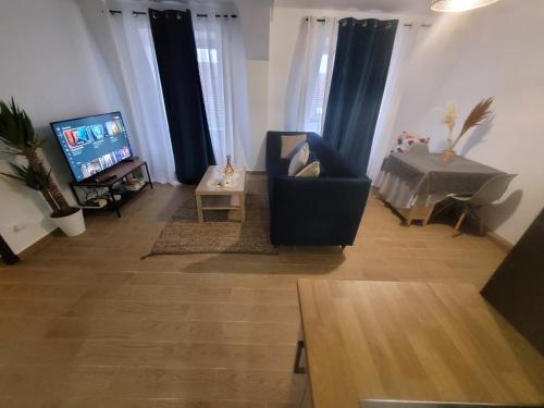 a living room with a chair and a television at Coquet appartement à 15mn de Paris et 10 mn de Stade de France, wifi, Netflix, in Groslay