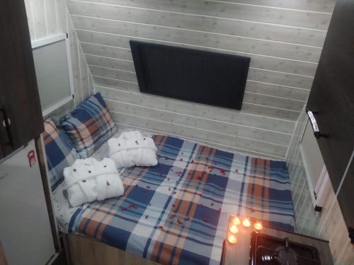 una piccola camera da letto con letto con cuscini e TV di Tak Tak Karavan kiralama hizmeti a Manavgat