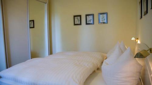 1 cama con sábanas blancas y almohadas en una habitación en Haus am Steinberg, en Bad Driburg