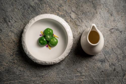 a plate with green peppers on it next to a vase at Monastero Sant'Alberico Relais in Balze