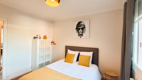 a bedroom with a bed with yellow pillows at Foucault - Appartements - au cœur de Lourdes in Lourdes