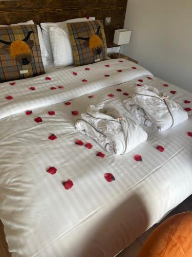 a bed with red rose petals on it at Whitemoss Lodge in Dunning