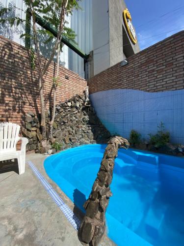 einen Pool in einem Garten mit einer Steinmauer in der Unterkunft Hostel Ruca Potu in Mendoza