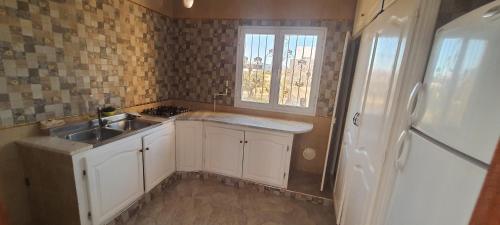 a kitchen with white cabinets and a sink and a window at Dar souade chatt mariem in Sousse