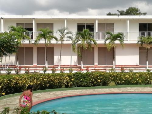 a woman standing next to a swimming pool in front of a hotel at Hotel parador tropical in Cartagena de Indias