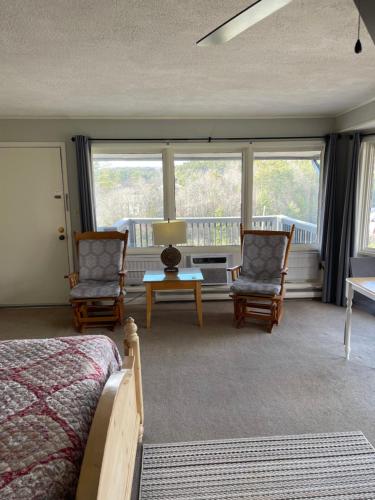 a bedroom with two chairs and a bed and windows at Cliff Dwellers Inn in Blowing Rock