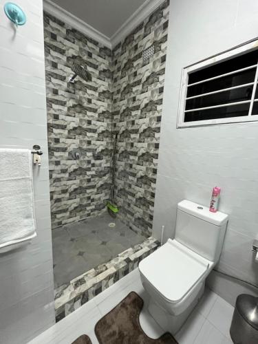 a bathroom with a toilet and a stone wall at Onelove Homes in Lusaka