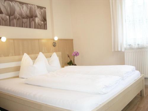 a white bed with white pillows in a bedroom at Apart Ahorn in Finkenberg