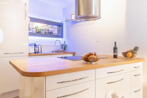 a kitchen with white cabinets and a wooden counter top at Seeblick-Oase IStayUnixI Seenähe-Sauna-Balkon-Netflix-Parkplatz in Öhningen