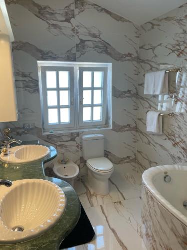 een badkamer met 2 wastafels, een toilet en een bad bij The Dragonfly Retreat in Málaga