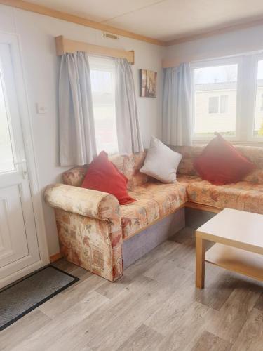 a couch with red pillows sitting in a living room at Sunrise Holidays Skegness - Ruby in Skegness