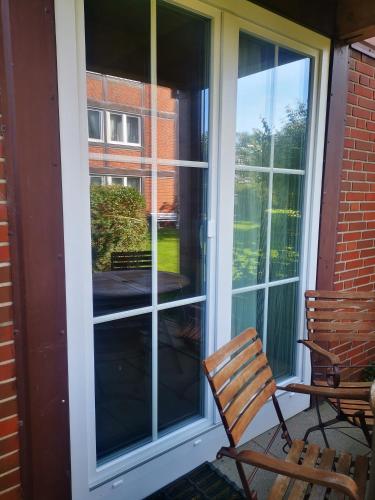 a screened in porch with a chair and a window at Kleine Ella Pellworm in Pellworm