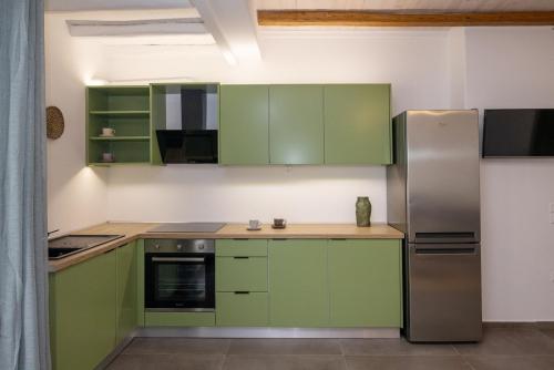 a kitchen with green cabinets and a stainless steel refrigerator at Raffar luxury houses in Tinos Town