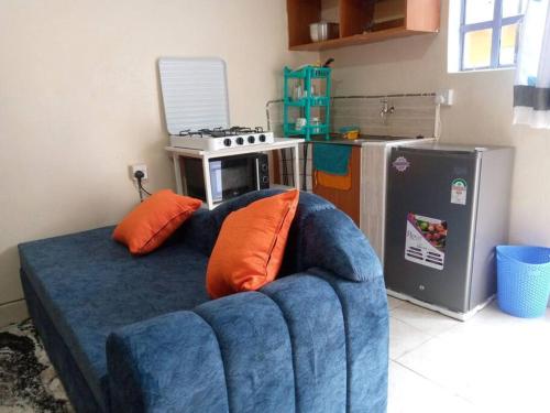 - un canapé bleu avec des oreillers orange dans la cuisine dans l'établissement Atiram furnished apartments, à Nakuru