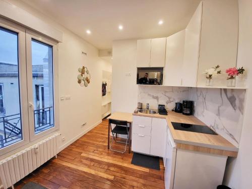 uma cozinha com armários brancos e uma grande janela em Charmant studio Ménilmontant em Paris
