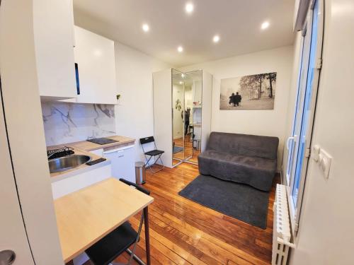 eine Küche und ein Wohnzimmer mit einem Sofa in der Unterkunft Charmant studio Ménilmontant in Paris