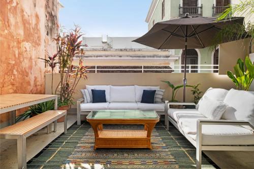 een patio met banken, een tafel en een parasol bij Tizol Historic Building 8br in Old San Juan in San Juan