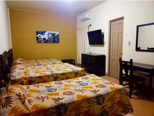 a bedroom with two beds and a desk and a television at Hotel Los Monteros in Ciudad Victoria