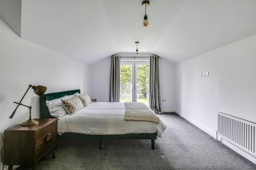 a white bedroom with a bed and a window at Moselle House in Biggin Hill