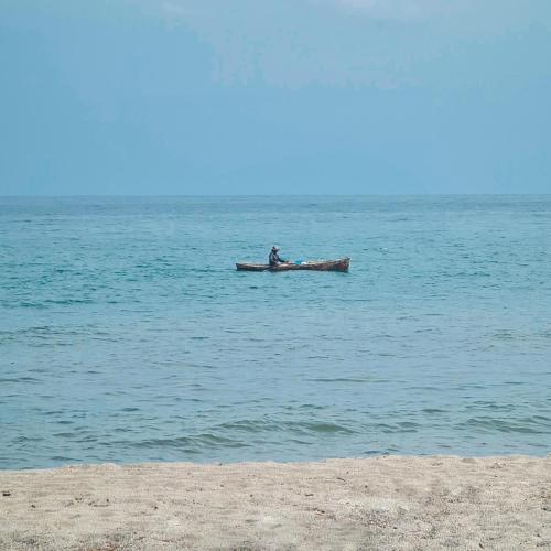 a man is sitting in a boat in the water at Hotel Partenon Beach in La Ceiba