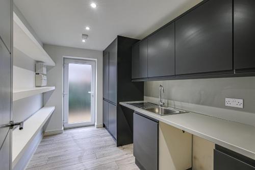 a kitchen with black cabinets and a sink at Moselle House in Biggin Hill