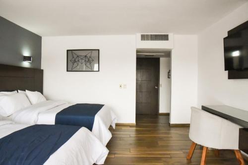 a hotel room with two beds and a desk at Hotel Expo Plaza Business and Family Guadalajara in Guadalajara