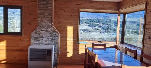 een kamer met een tafel in een kamer met ramen bij GLAMPING CABAÑA HOLMBERG in Coihaique