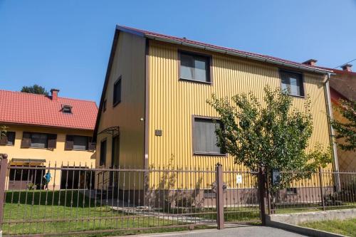 a yellow house with a fence in front of it at Apartmani Rumora Gorski kotar in Tuk Vojni