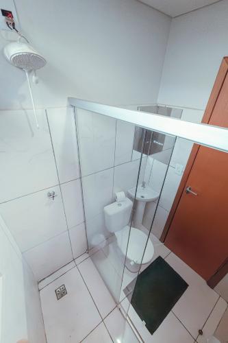 a white bathroom with a toilet and a sink at Hotel Apiacas in Ribeirão Preto