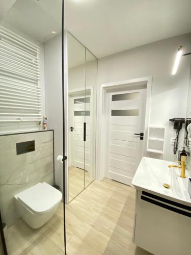 a bathroom with a toilet and a glass shower at Apartament Środowa by Prestige Home in Szczecin