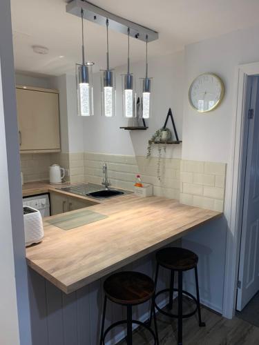 een keuken met een aanrecht en twee barkrukken bij SUNNY RHYL BUNGALOW in Rhyl