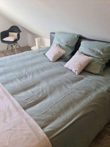 a large bed with pillows on it in a bedroom at Charmante maison Les Cèdres Bleus in Loon-Plage