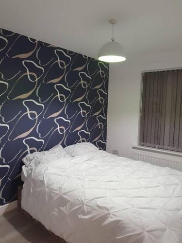 ein Schlafzimmer mit einem Bett mit einer blau-weißen Wand in der Unterkunft Home near Rugby Station for contractors and Work Commuters, 5 bedroom, Free Parking & Garden 